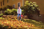 Photo of Craftsman CMCBL700D1 leaf blower in use outdoors, scattering autumn leaves in front of a yellow house.